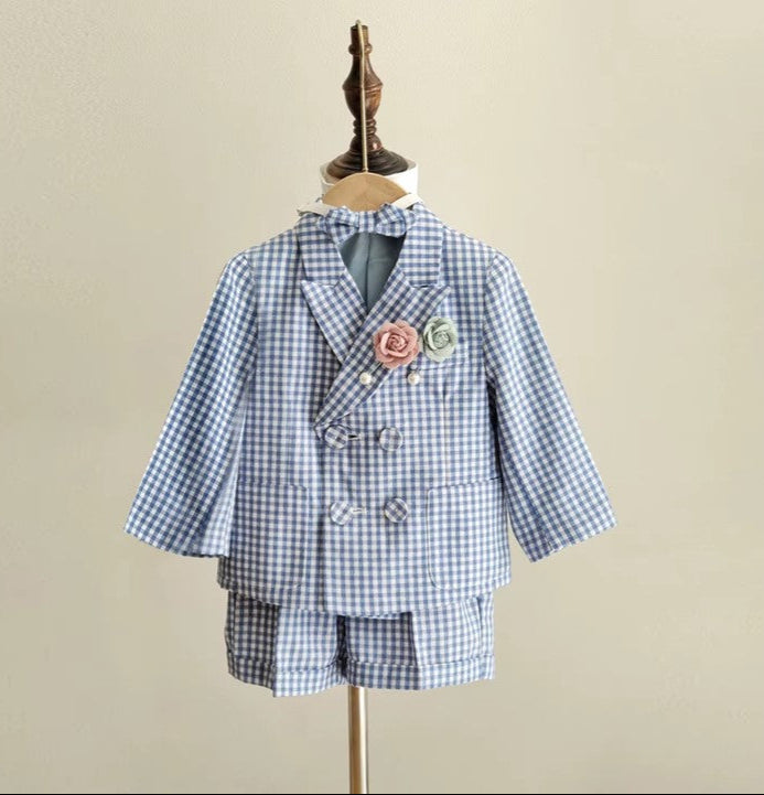 Full front view of the blue gingham boy wedding outfit featuring a double-breasted blazer, tailored shorts, and floral pins in blush and green. Ideal for formal events.