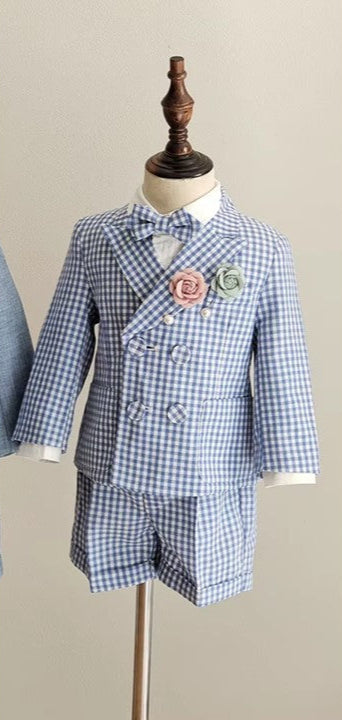 Front view of the charming blue gingham boy wedding outfit featuring a double-breasted blazer, tailored shorts, and floral pins. Perfect for formal occasions.