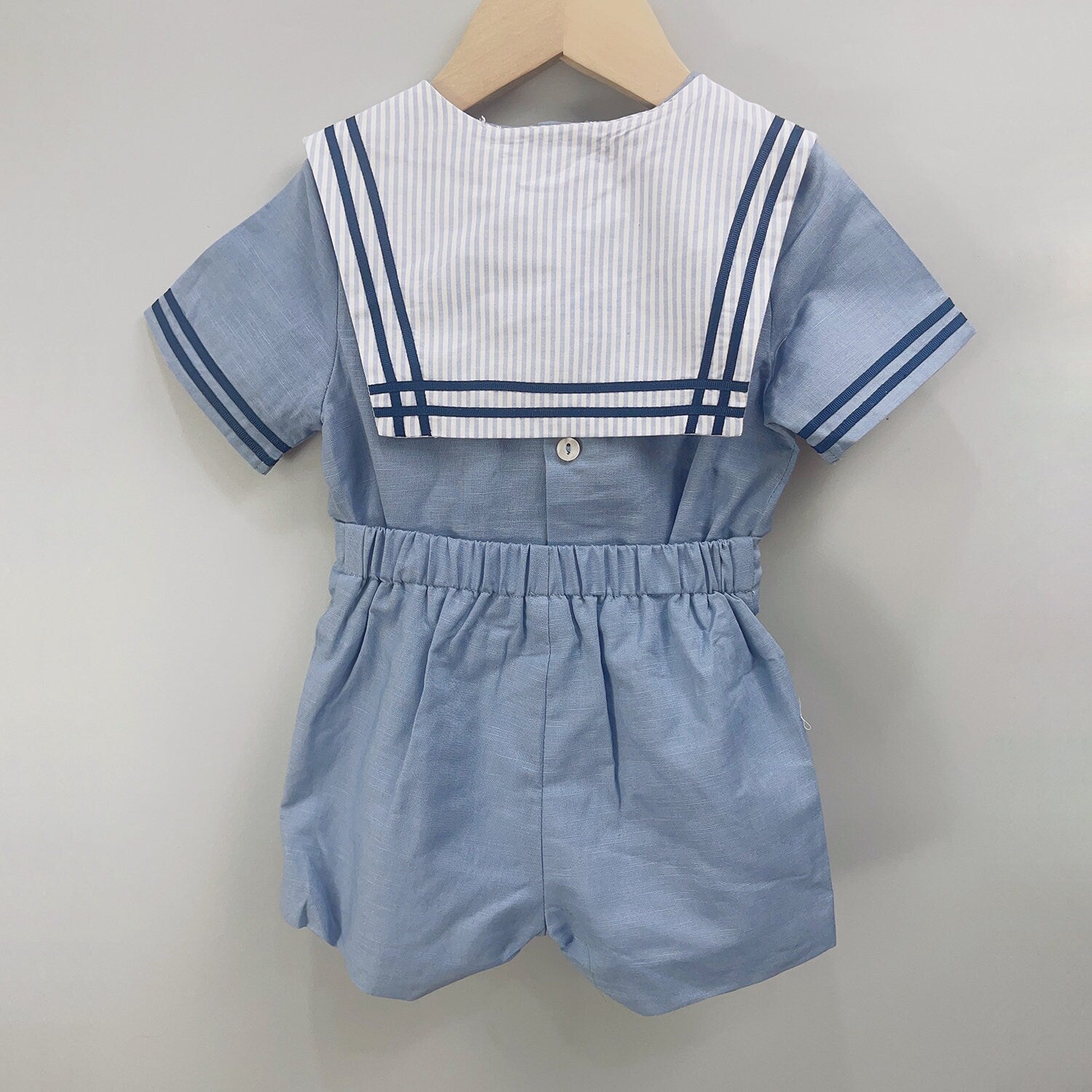 Back view of classic sailor-style boys' outfit featuring a nautical striped collar and light blue fabric, designed for special occasions like christenings, birthdays, and weddings for boys aged 12 months to 6 years.